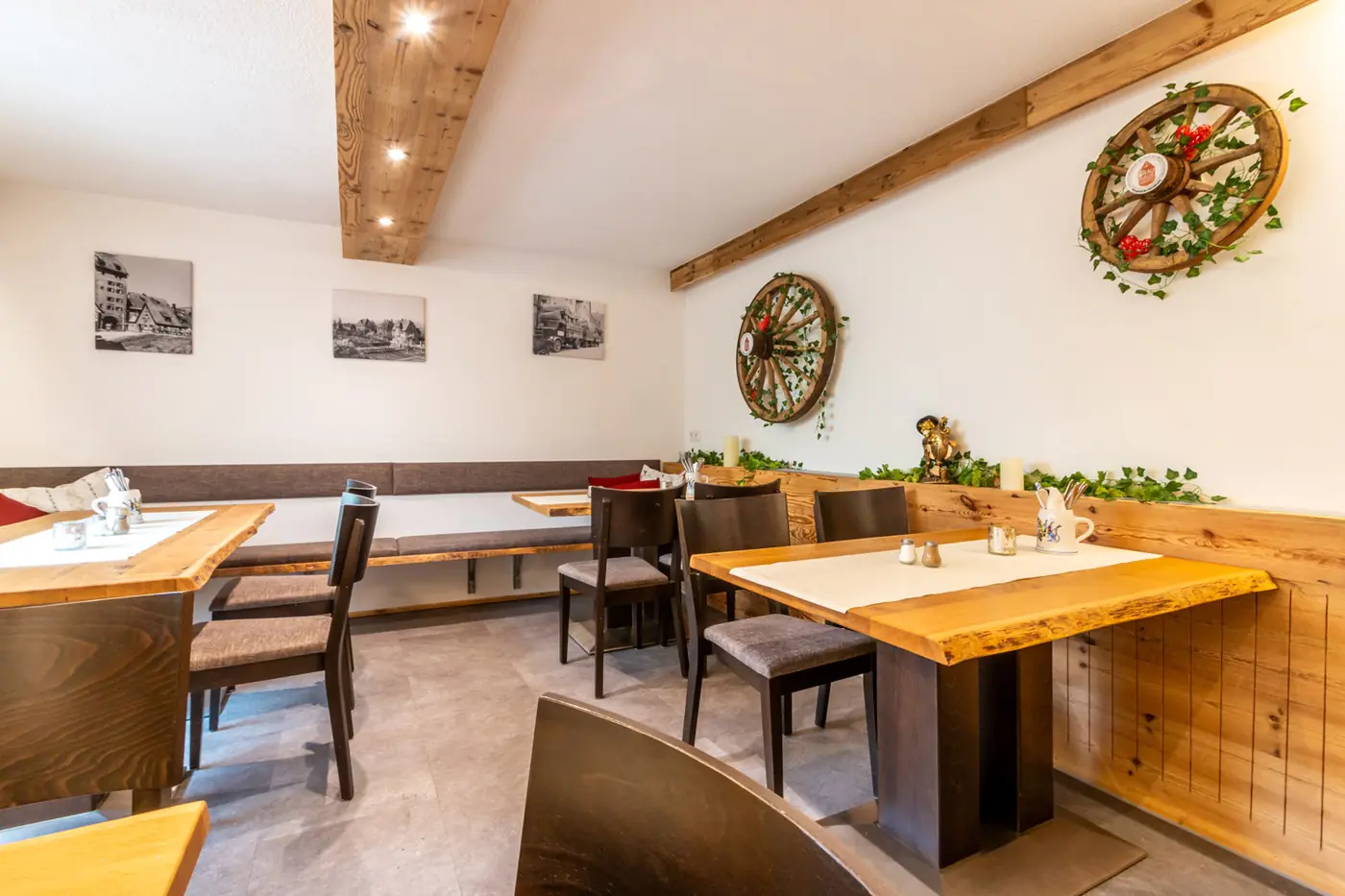 Gastraum des Brauhaus Hersbruck mit hellen Holztischen, Wagenrad an der Wand und gerahmten alten Fotos